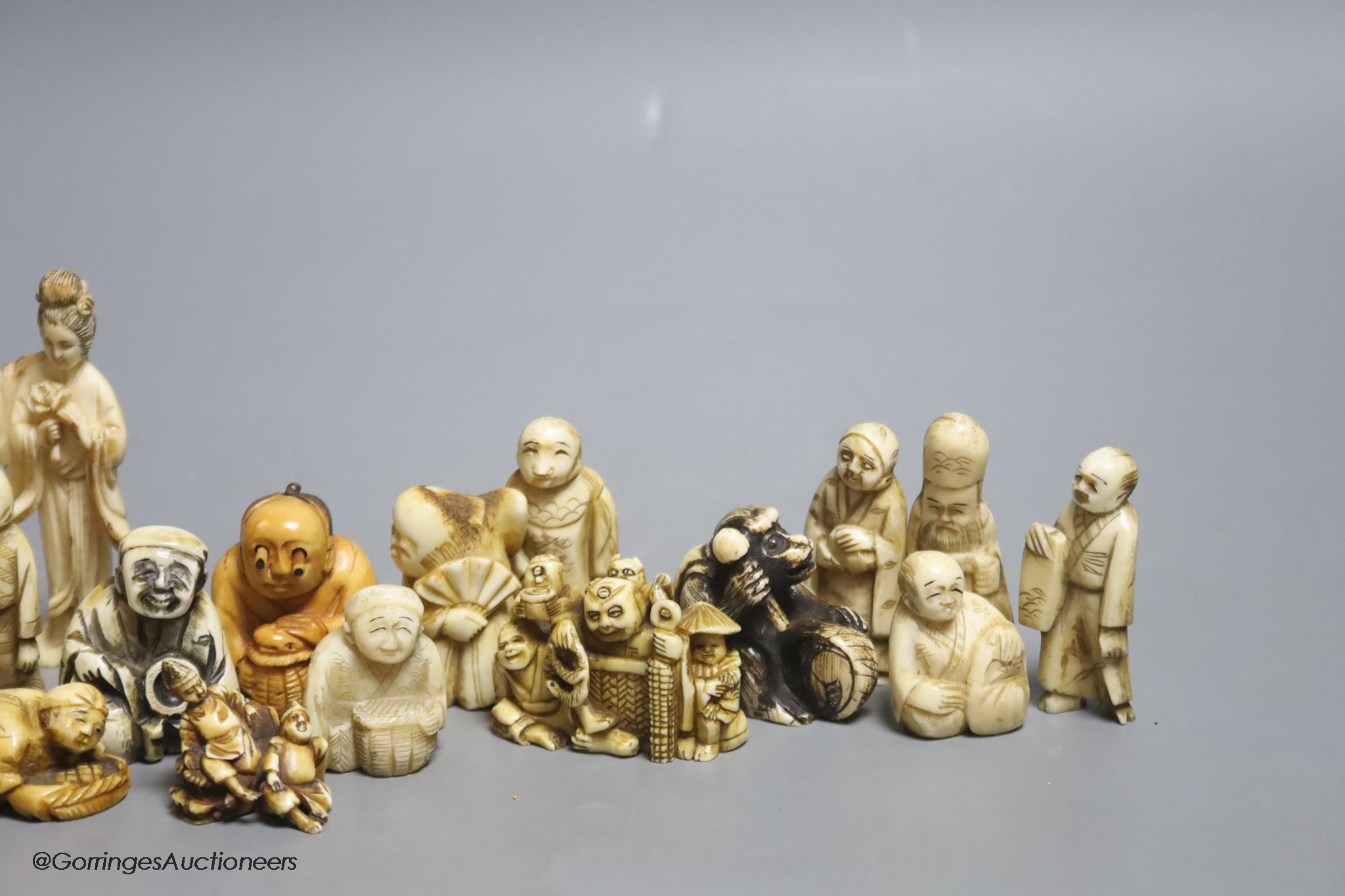 Fourteen Japanese ivory netsuke, a Chinese ivory group and elephant figure, all early 20th century